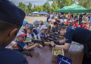 Dzieci na stoisku policyjnym podziwiają broń