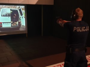 Policjant podczas szkolenia strzeleckiego, kształci swoje umiejętności przy pomocy systemu Lasershot. System działa na zasadzie strzelnicy wirtualnej, gdzie funkcjonariusze ćwiczą z użyciem broni palnej w warunkach zbliżonych do rzeczywistości.