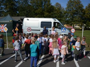 Wykładowcy Zakładu Ruchu Drogowego oraz Służby Prewencyjnej prezentują dzieciom stoisko profilaktyczne podczas pikniku z okazji 100-lecia Centrum Szkolenia Łączności i Informatyki w Zegrzu.