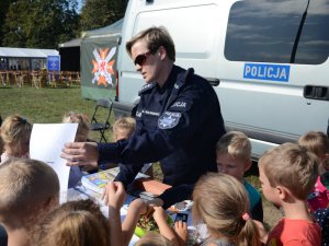 Wykładowcy Zakładu Ruchu Drogowego oraz Służby Prewencyjnej prezentują dzieciom stoisko profilaktyczne podczas pikniku z okazji 100-lecia Centrum Szkolenia Łączności i Informatyki w Zegrzu.