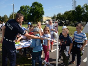 Wykładowcy Zakładu Ruchu Drogowego oraz Służby Prewencyjnej prezentują dzieciom stoisko profilaktyczne podczas pikniku z okazji 100-lecia Centrum Szkolenia Łączności i Informatyki w Zegrzu.